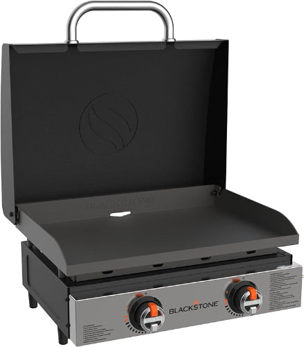 A compact Blackstone tabletop griddle with a protective hood and two heating elements visible at the bottom. The griddle is black, and the brand's logo is visible on the front.