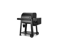 A black pellet grill with a side table and a fuel hopper on wheels, shown from a three-quarter angle on a solid white background.